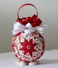 a red and white ornament with a bow on it