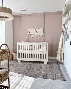 a baby's room with pink walls and white crib in the corner, along with wicker baskets on the floor