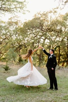 a bride and groom dancing in the grass