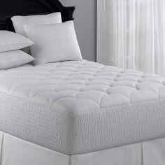 a bed with white sheets and pillows on it