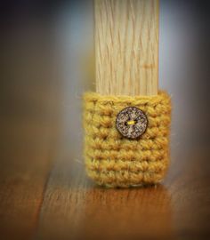 a small yellow crocheted cell phone case with a button