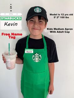 a young boy wearing an apron and holding a starbucks drink