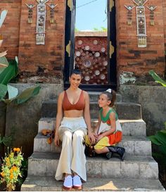 two women sitting on steps in front of a building