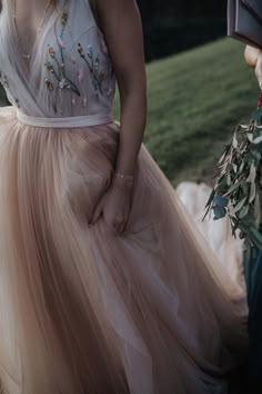 a woman in a long dress holding flowers