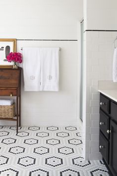 a bathroom with black and white tile flooring, sink, mirror and towel rack