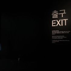 a man standing in front of a black wall with the words exit written on it