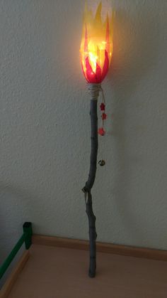 a lit up fire stick on top of a wooden table next to a white wall