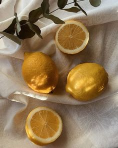 three lemons are sitting on a white cloth