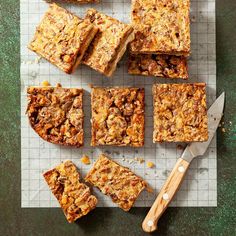 several pieces of dessert sitting on top of a cutting board next to a spatula