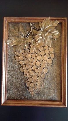 a wooden frame holding a bunch of penns and a metal leaf on top of it