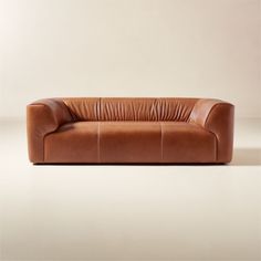 a brown leather couch sitting on top of a white floor next to a beige wall