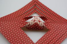 an origami bird made out of red and white paper