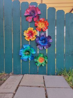 colorful paper flowers are hanging on a fence