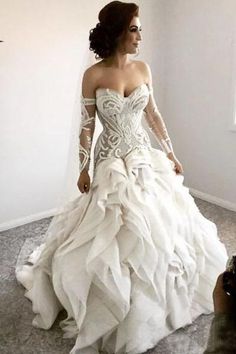 a woman in a white wedding dress standing next to a window