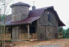 an old barn with a red roof and two tall towers on the side of it