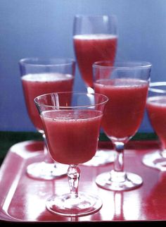 four glasses filled with liquid sitting on top of a table