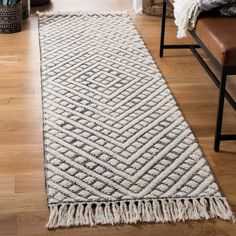 a white rug with fringes on the floor in front of a couch and chair