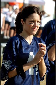 a girl in a football uniform holding her hands together