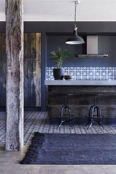 a kitchen with blue and white tiles on the walls, counter tops and stools