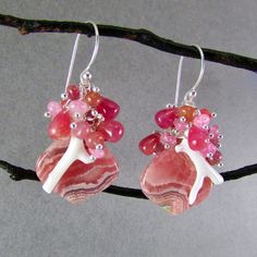 I love these focals! They are Argentine rhodochrosite gems and measure 22x20mm. They have been wrapped in sterling silver wire and dangle below a gorgeous combination of smooth ruby briolettes, pink moonstone, pink sapphire, white branch coral. Each bead is meticulously wrapped onto it's own head pin. The entire cluster is topped. I have used simple sterling ear wires. The earrings measure 1 3/4 (44mm.) from the top of the ear wires. Unique Pink Jewelry With Gemstone Accents, Sterling Silver Pink Wire Wrapped Earrings, Pink Sterling Silver Wire Wrapped Earrings, Handmade Coral Sterling Silver Jewelry, Pink Gemstone Accented Earrings For Gift, Pink Gemstone Accents Earrings For Gifts, Pink Gemstone Earrings For Gift, Unique Pink Gemstone Earrings, Pink Earrings With Gemstone Accents For Gift