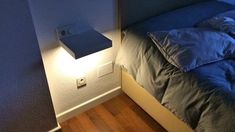 a bed with a blue comforter next to a night stand on the side of a wall