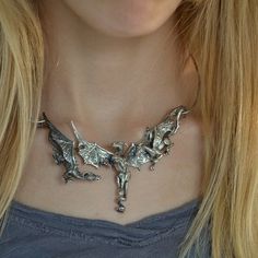 "Three magnificent dragons take flight in this stunning piece of sterling silver fantasy jewelry. The concept of the dragon necklace features three dimensional sculptures and an unique front clasp subtly incorporated into the design of the neckpiece; the result is a dragon trio statement necklace that seem to float around the wearer's neck, an artisan's creation that is sure to draw the eye of all who see it. Each of the dragons has a unique personality; the central dragon is the leader of the g Dragon Jewelry Clay, Silver Fantasy Jewelry With Dragon Design, Fantasy Silver Jewelry With Dragon Design, Fantasy Style Silver Jewelry With Unique Design, Elegant Silver Jewelry For Fantasy Events, Silver Dragon Design Collectible Jewelry, Silver Dragon Design Jewelry For Fantasy Events, Silver Necklace For Fantasy Events, Collectible Metal Jewelry With Dragon Design