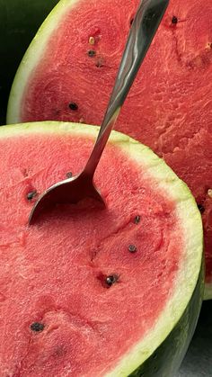 a knife sticking out of the inside of a watermelon cut in half to eat