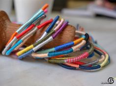 a bunch of bracelets that are on top of a wooden object with strings attached to them