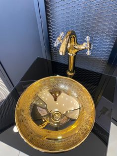 a gold colored sink in a bathroom next to a black cabinet with glass doors on it