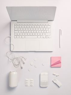 an open laptop computer sitting on top of a white desk next to other office supplies