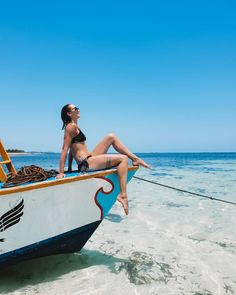 a woman laying on top of a boat in the ocean