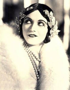 an old photo of a woman wearing pearls and a fur coat with her eyes closed