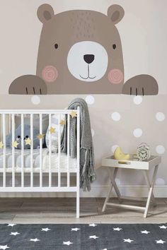 a baby's room with a teddy bear decal on the wall and a crib