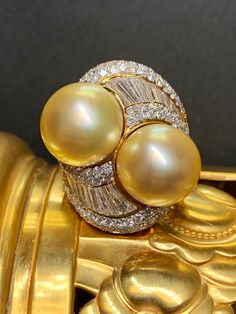 If you have ever wanted a ring with a presence, look no further. This fabulous piece is done in 18K yellow gold and set with approximately 4.50cttw in G-I color Vs1-Si1 clarity round and oversized, tapered baguette diamonds. Sitting next to each other are two natural golden South Sea pearls measuring 13mm and 13.40mm. What an incredible look! Dimensions/Weight .9" wide by 1.1" top to bottom. Size 5 3/4 (sizable). Weighs 15.3dwt Condition Light scuffs on the bottom of the shank, but in perfectly Luxury High Luster Oval Pearl Ring, Luxury Oval Pearl Ring With Brilliant Cut, Luxury Yellow Diamond Ring Hallmarked, Luxury Gold Pearl Ring With High Luster, Luxury Yellow Diamond Hallmarked Ring, Luxury High Luster Gold Pearl Ring, Exquisite Gold Diamond Ring Gia Certified, Gold Pearl Ring With Brilliant Cut Oval, Gold Oval Pearl Ring With Brilliant Cut