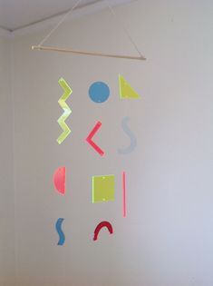 a white wall with various colored shapes hanging from it's sides and on the ceiling