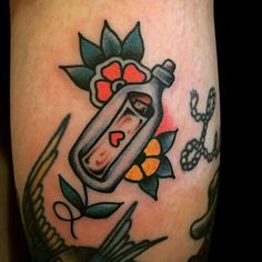 a tattoo with a bottle and flowers on it