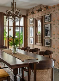 a dining room table with chairs and pictures on the wall