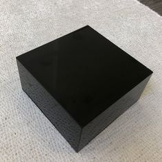 a black square object sitting on top of a white carpeted floor next to a wall