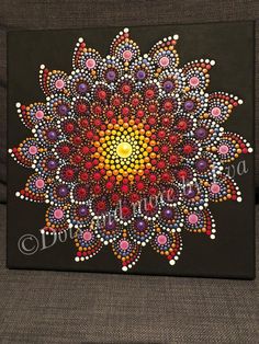 a painting on a black canvas with colorful dots in the shape of a sunflower