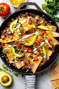 a skillet filled with nachos and tortilla chips