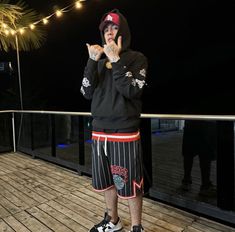 a young man standing on top of a wooden deck next to a palm tree at night