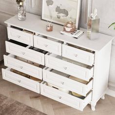 a white dresser with drawers and pictures on the wall