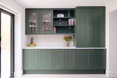 a kitchen with green cabinets and white counter tops