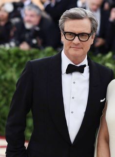 an older man and woman in tuxedos pose for the camera on the red carpet