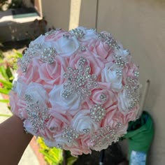 a bridal bouquet with pink roses and diaper on the bride's arm