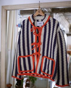 an orange and blue striped jacket hanging on a mirror