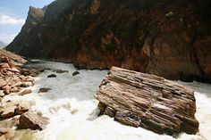 the water is white and choppy in this river with large rocks on both sides