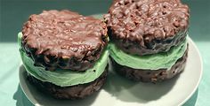 two chocolate ice cream sandwiches on a white plate with green frosting and sprinkles