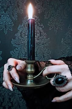 a woman holding a candle in her hands with a ring on it's finger