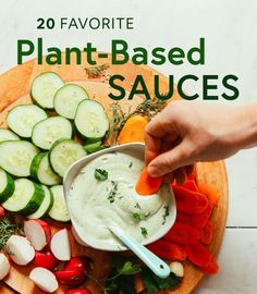 a person is dipping sauce into vegetables on a cutting board